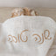Loaf of bread wrapped in a white cloth with 'Artisan' embroidery on a neutral background