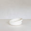 White ceramic bowl on a light gray surface with a white background