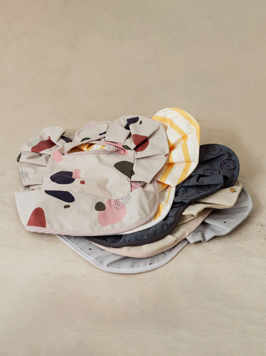 An assortment of Trend{ING}s playful baby bibs piled on top of each other
