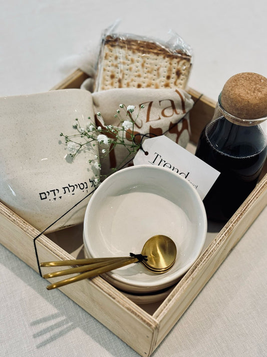 Trend-ings Seder in a Box for Pesach, including Linen matzah cover, 3 dipping holes, a nordic hat with kosher for Passover grape give, matte gold round teaspoons and a stone matte ritual cup, all wrapped in a wooden recyclable box