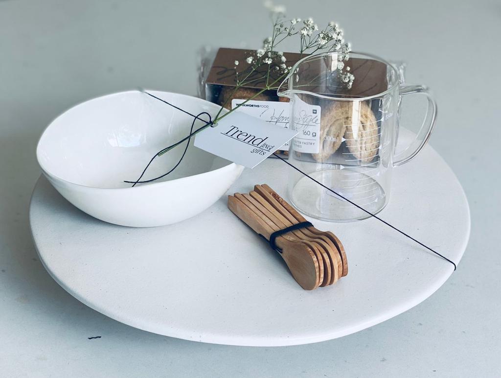 Trend-ing's Bakers Delight Baking Gift box, featuring a ceramic cake stand , glass measuring cup, wooden spoons and crunchy palmier biscuits