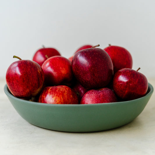 Trend{ING}s Acacia small stone salad bowl in green, holding a bunch of bright red apples