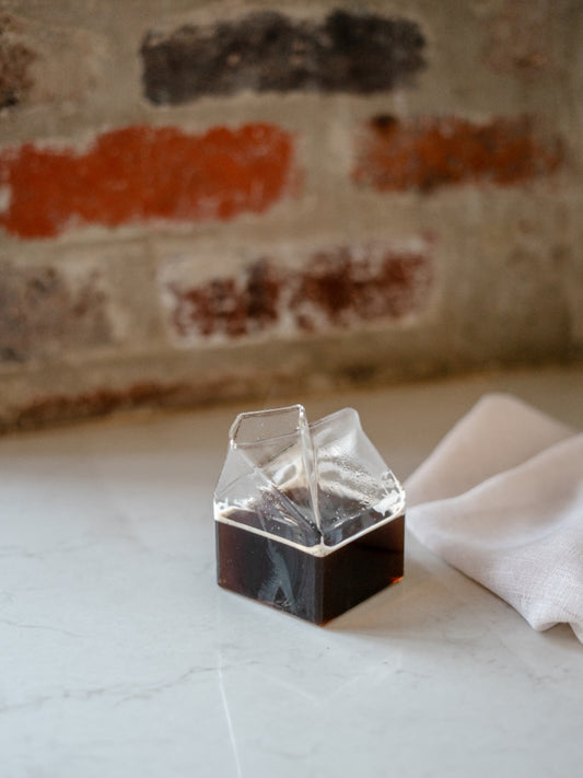 Trend{ING}s  Milk Carton Glass Jug with black coffee and a napkin beside it
