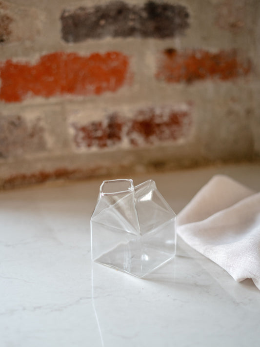 Trend{ING}s empty Milk Carton Glass Jug with a napkin beside it