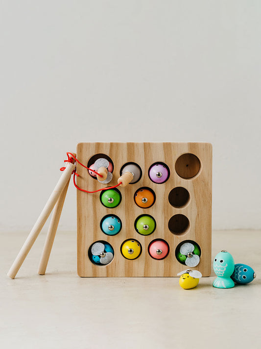 Trend-ings Baby Wooden Fishing Game with colourful bees in holes and a rod with magnets to fish them out; a few fish are out and next to the game