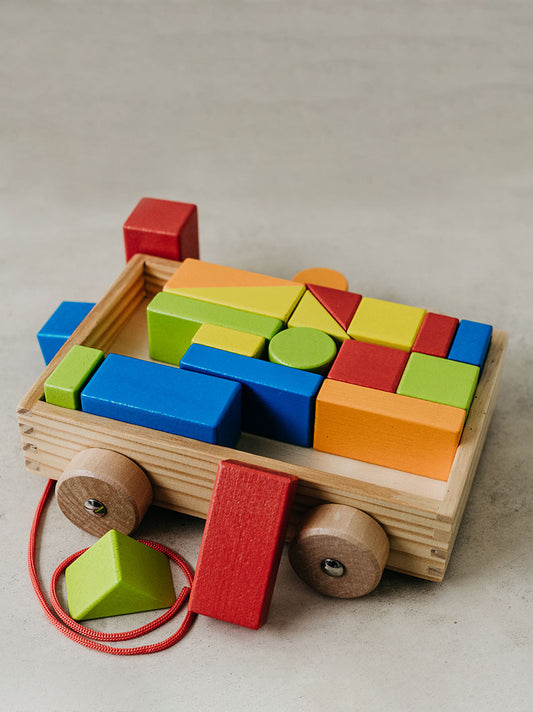 Trend-ing Baby's building blocks on wheels colurful geometric game in a pull trolley with some blocks out and to the side