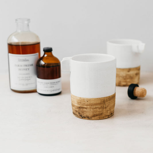 Two of Trend{ING}s Honey Jug in Natural wooden bottom, with two amber jars of honey in the background