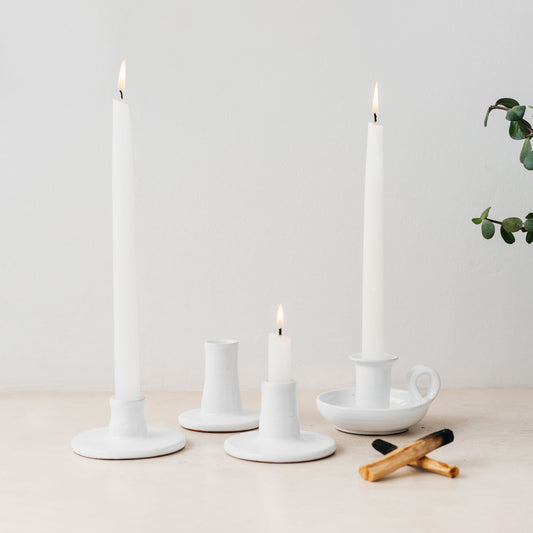 Trend{ING}s White gloss ceramic candle holders standing together on a table with 3 different sizes and lit candles inside them