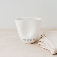 Trend{ING}s Ritual Ceramic Cup in white colour with a blessing next to linen placemats