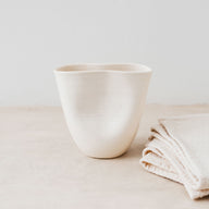 Trend{ING}s Ritual Ceramic Cup in oatmeal colour next to linen placemats