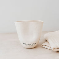 Trend{ING}s Ritual Ceramic Cup in oatmeal colour with a blessing next to linen placemats