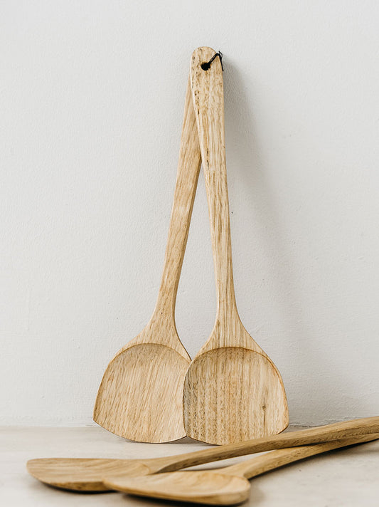 Trend-ings Walnut Wood Salad Servers standing upright against a wall and another pair laying flat in front of it