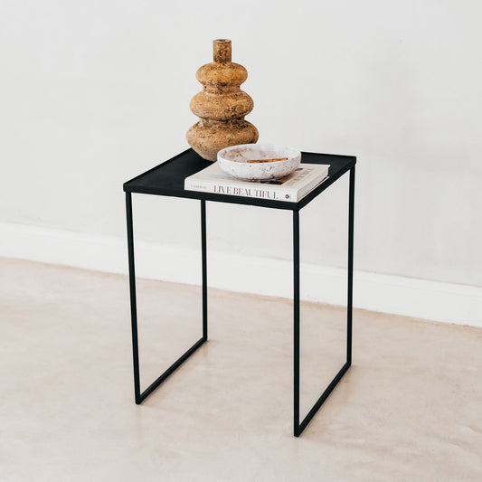 Trend-ings steel side/occasional table with a book, bowl and vase on it