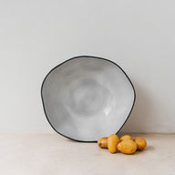 Trend{ING}s Drunken Stone Salad Bowl in Basalt finish; Viewed head on with a few baby potatoes beside it