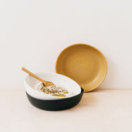 Trend{ING}s Wren Stone Breakfast Bowls in White Speckled, Brown Ochre & Coal Black; viewed head on stacked together with some breakfast porridge in one