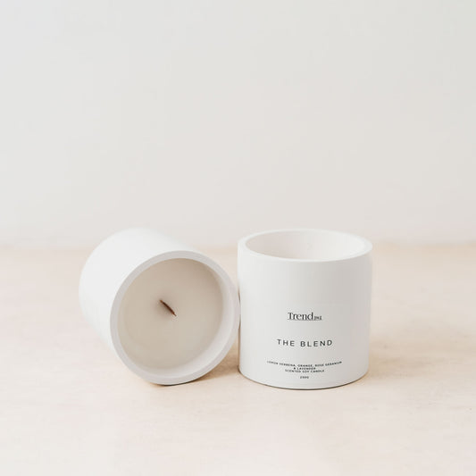 Trend{ING}s white wooden wick candle; 2 candles next to each other and one lying on its side with the Trend{ING} branding
