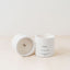 Trend{ING}s white wooden wick candle; 2 candles next to each other and one lying on its side with the Trend{ING} branding