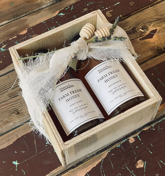 Trend{ING}s Artisanal Honey Box, featuring two glass amber bottles of different honey and two wooden dippers wrapped in a wooden box