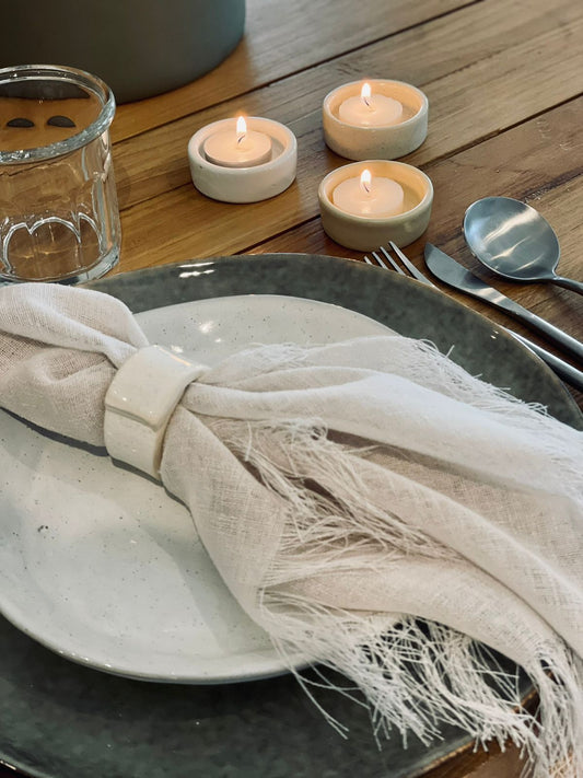 Trend{ING}s Ceramic Napkin Ring slid onto a linen napkin at a place mat at the table